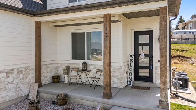 Property entrance featuring central AC unit, a porch, stone siding, and a shingled roof | Image 6