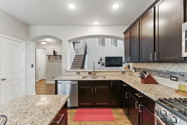 Kitchen featuring appliances with stainless steel finishes, light stone countertops, decorative backsplash, arched walkways, and a sink | Image 14