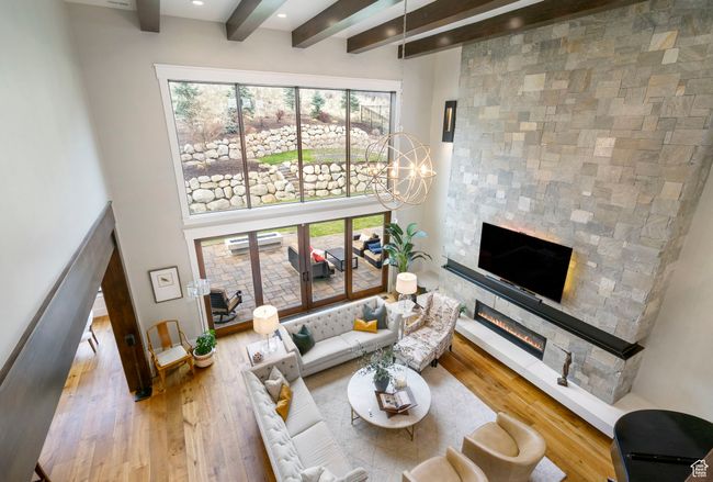 Living area with a glass covered fireplace, wood-type flooring, beamed ceiling, and a healthy amount of sunlight | Image 63