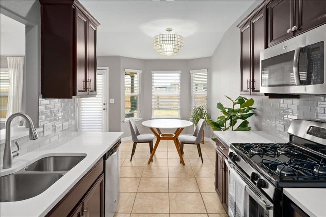 Kitchen with tasteful backsplash, a sink, light tile patterned floors, light countertops, and appliances with stainless steel finishes | Image 12
