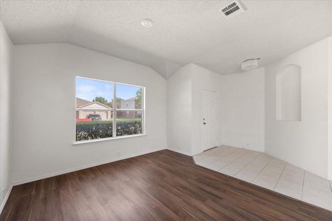 Looking toward toward the front door from the living/dining with wood finished floors, vaulted ceiling, a textured ceiling, and baseboards | Image 19