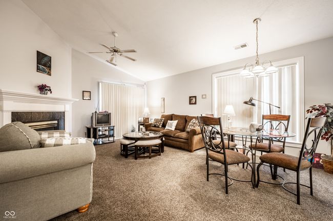 living room featuring vaulted ceiling, carpet floors, open concept and fireplace | Image 8