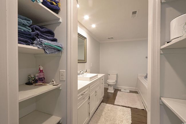 Bathroom with vanity, ornamental molding, wood finished floors, and a tub | Image 13