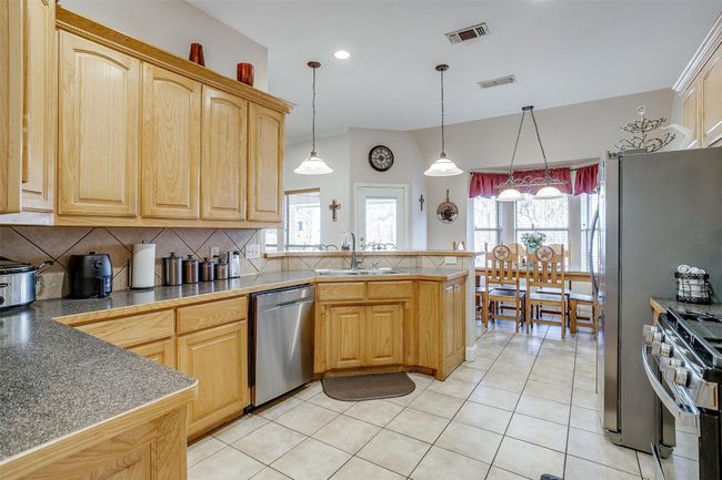 Kitchen with a peninsula, visible vents, a sink, and appliances with stainless steel finishes | Image 5