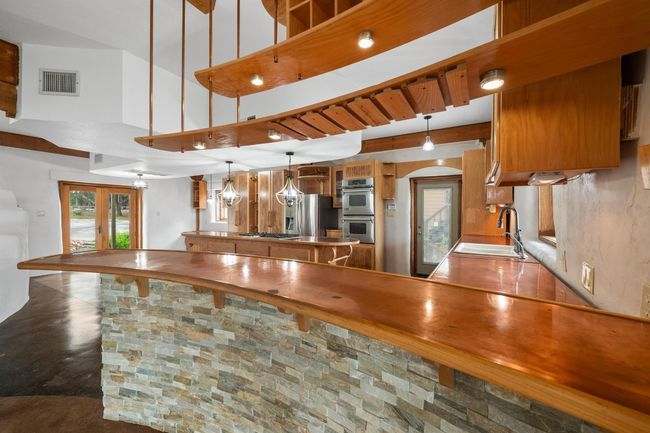 Kitchen with a sink, appliances with stainless steel finishes, brown cabinetry, a peninsula, and arched walkways | Image 7
