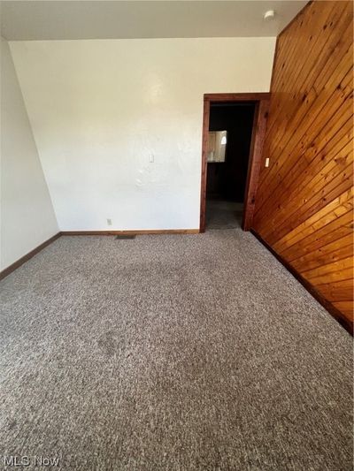 Spare room with lofted ceiling, wood walls, and carpet floors | Image 3