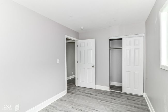unfurnished bedroom featuring wood finished floors, baseboards, and a closet | Image 17