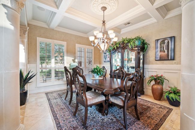 Dining area with coffered ceiling, crown molding, beamed ceiling, a chandelier, and wainscoting | Image 14