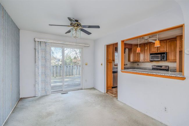 Kitchen with a ceiling fan, light colored carpet, brown cabinets, decorative light fixtures, and stainless steel appliances | Image 7
