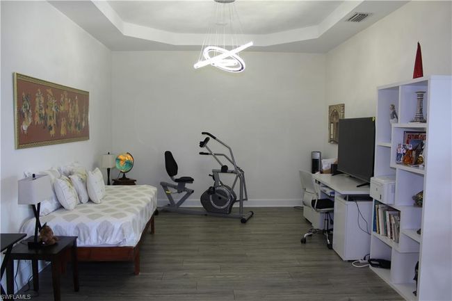 Open Den with visible vents, a notable chandelier, wood finished floors, and a tray ceiling | Image 14