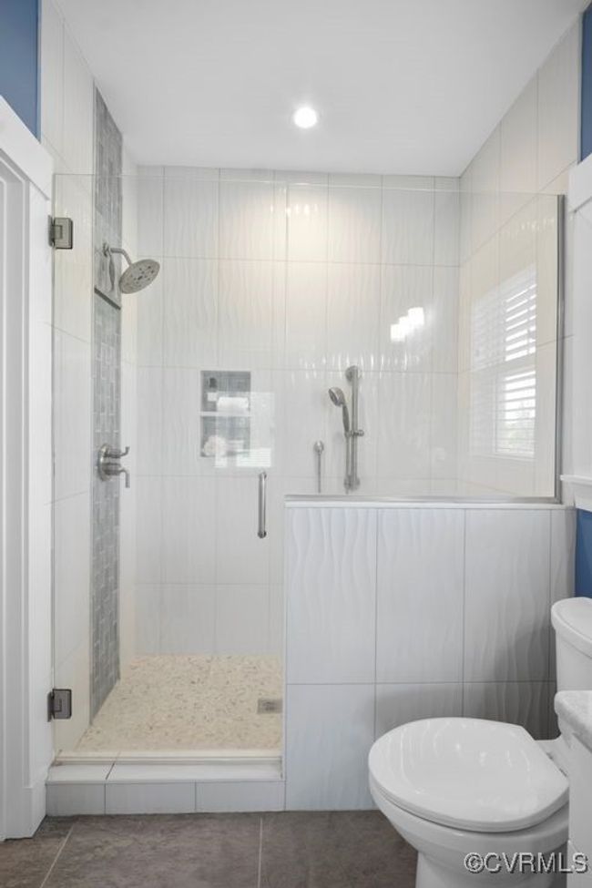 Full bathroom with tile walls, toilet, and a stall shower | Image 18