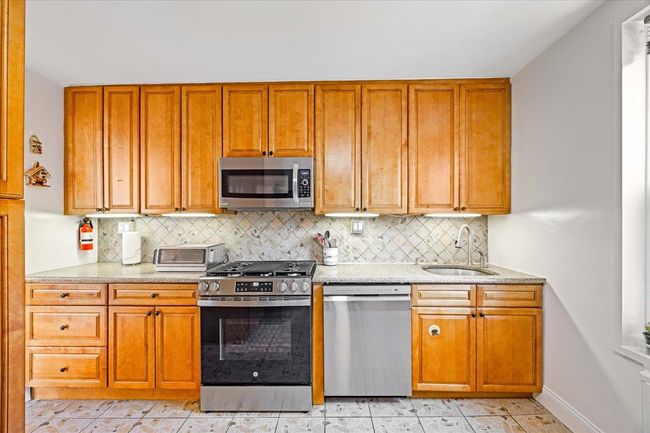Kitchen featuring stainless steel appliances, a sink, and brown cabinets | Image 7