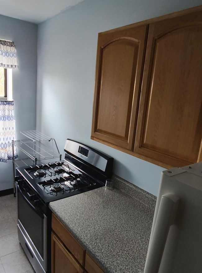 Kitchen with light tile patterned floors, brown cabinetry, and gas stove | Image 8