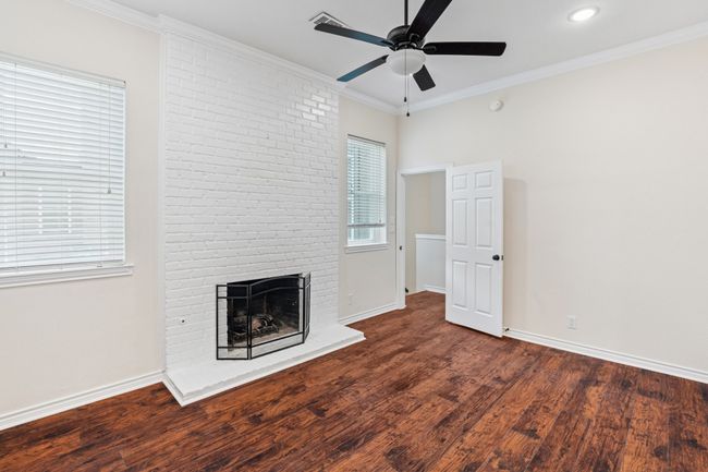 Unfurnished living room featuring ceiling fan, a brick fireplace, wood finished floors, ornamental molding, and recessed lighting | Image 15