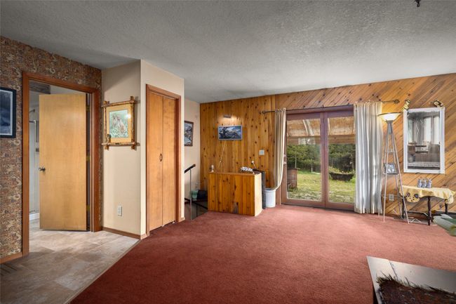 Living room with wood walls, carpet floors, and a textured ceiling | Image 32
