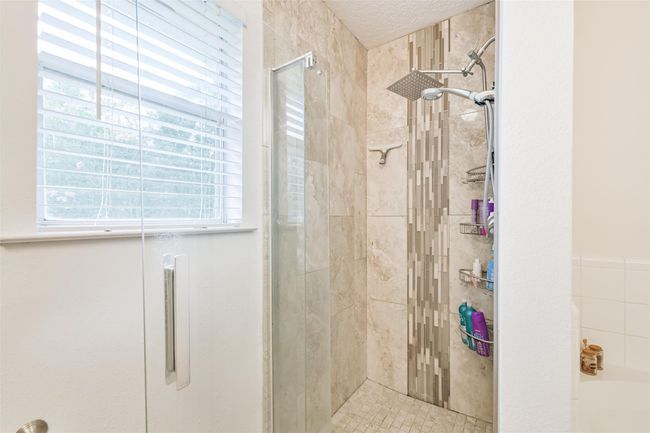 Updated primary shower with decorative mosaic tile accents, frameless glass door and overhead and hand held showerheads. | Image 14