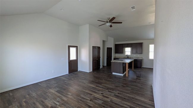 Kitchen featuring visible vents, open floor plan, dark wood-type flooring, a center island, and light countertops | Image 16
