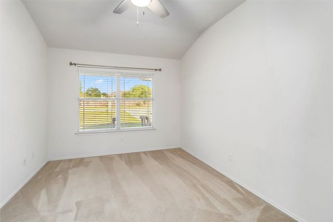 Empty room featuring a ceiling fan, light colored carpet, baseboards, and vaulted ceiling | Image 9