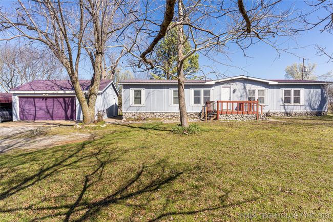 This home has been permanently affixed, has a concrete sidewalk and a detached garage with concrete flooring. There is also a carport and attached storage for those extra toys. | Image 4