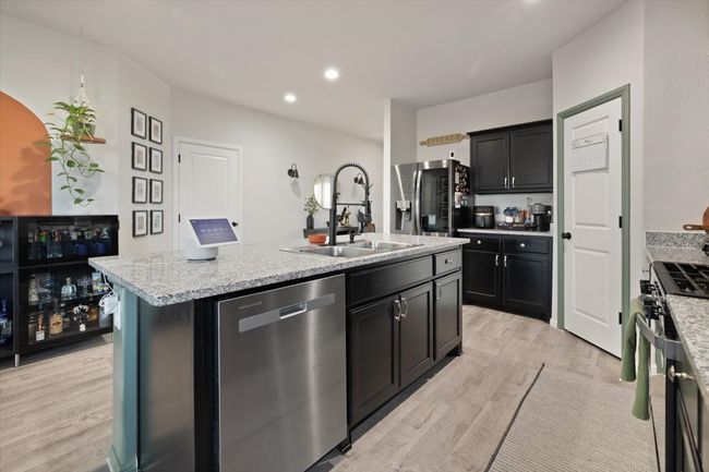 Kitchen featuring appliances with stainless steel finishes, a center island with sink, light ceramic tile flooring, and dark cabinetry | Image 14