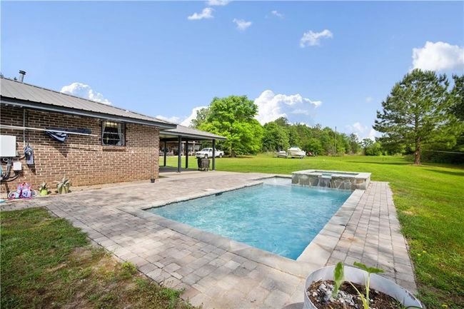 View of pool with a yard, a patio, and a pool with connected hot tub | Image 23