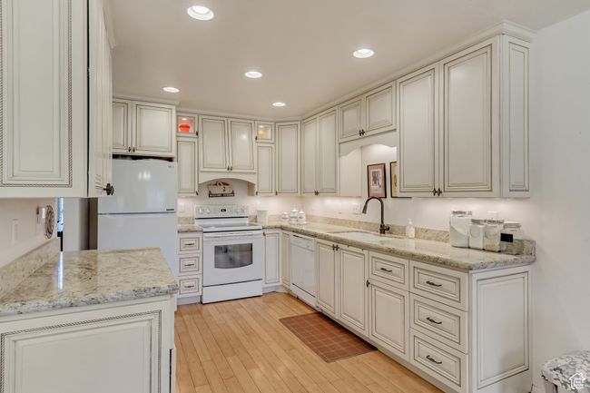Kitchen with white appliances, a sink, light wood-style floors, and light stone counters | Image 6