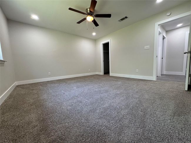 Carpeted empty room featuring ceiling fan, baseboards, visible vents, and recessed lighting | Image 21