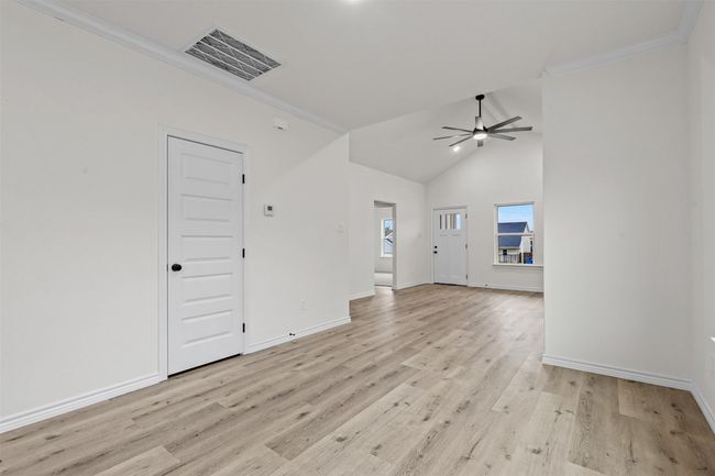 Unfurnished living room featuring high vaulted ceiling, light hardwood / wood-style flooring, ceiling fan, and ornamental molding | Image 8