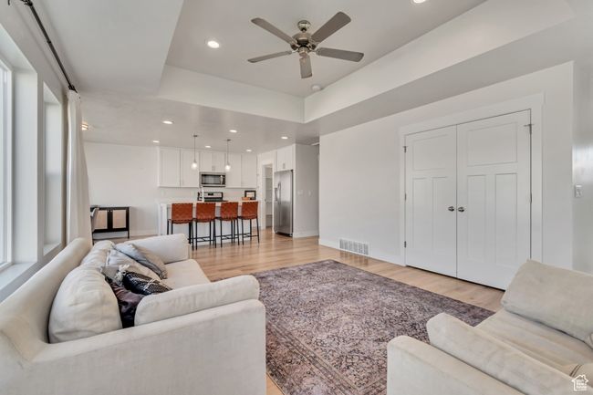 Living room featuring light wood-style flooring, ceiling fan, recessed lighting, and a raised ceiling | Image 12