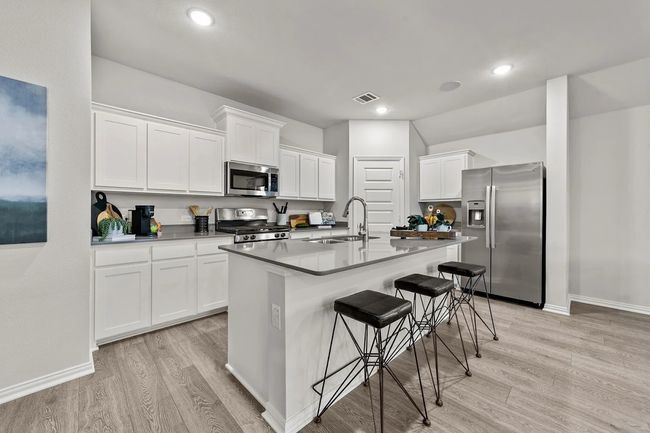 Kitchen with appliances with stainless steel finishes, light wood finished floors, a sink, a kitchen bar, and recessed lighting | Image 21