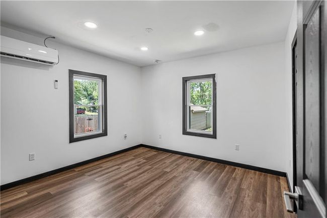 Empty room featuring a wall mounted AC, plenty of natural light, wood finished floors, recessed lighting, and baseboards | Image 34