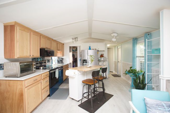 Kitchen featuring electric range oven, freestanding refrigerator, light wood-style flooring, light brown cabinets, and lofted ceiling | Image 13