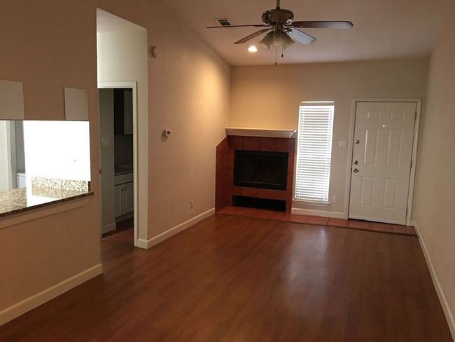 Unfurnished living room featuring a tiled fireplace, wood finished floors, visible vents, and baseboards | Image 12