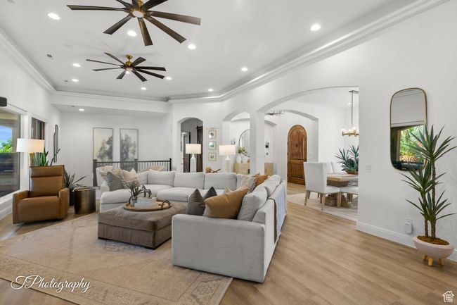 Living area featuring arched walkways, ceiling fan, light wood-style floors, ornamental molding, and recessed lighting | Image 23