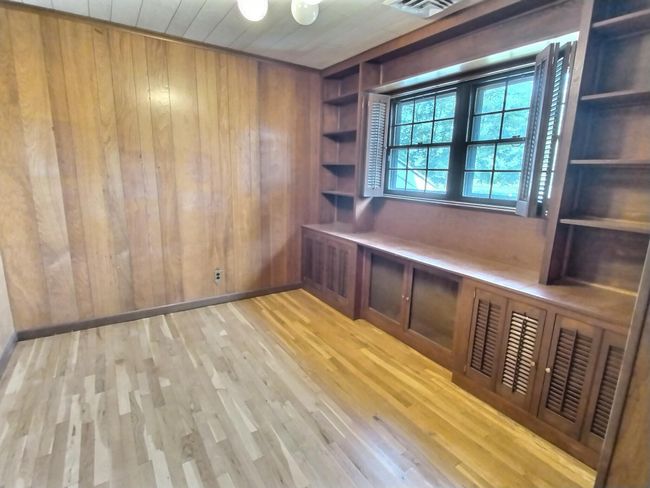 Unfurnished office featuring wooden walls, wood finished floors, baseboards, and built in shelves | Image 19