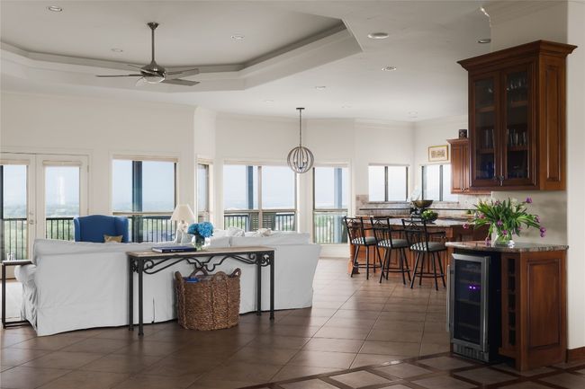 Living area with wine cooler, dark tile patterned flooring, plenty of natural light, ceiling fan, and ornamental molding | Image 16