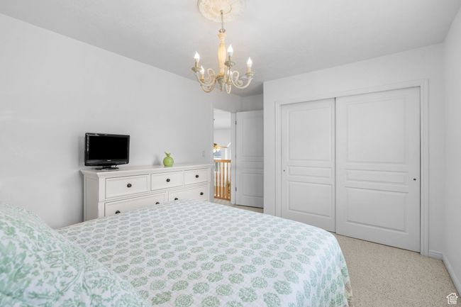 Bedroom with baseboards, a chandelier, light carpet, and a closet | Image 27