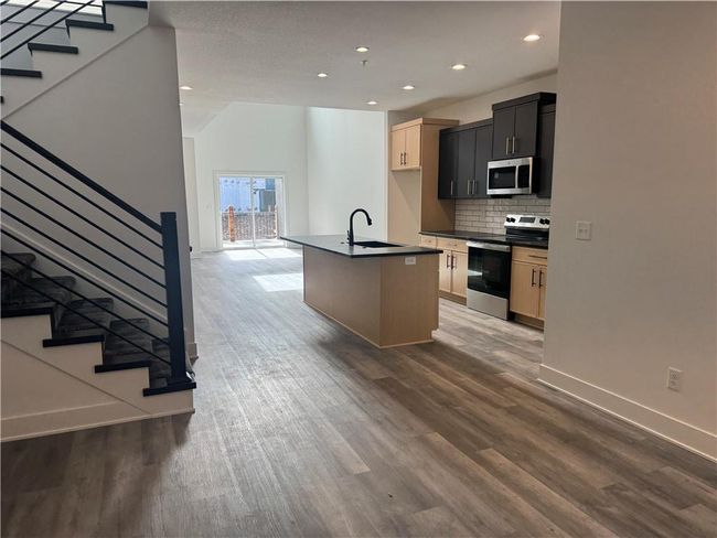Kitchen with a sink, dark countertops, wood finished floors, and appliances with stainless steel finishes | Image 6