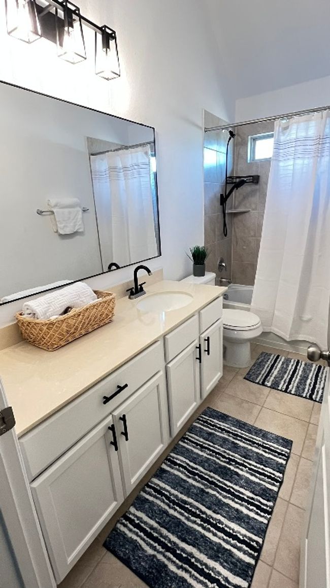 Bathroom 2 featuring tile patterned floors, vanity, shower / tub combo, toilet, and lofted ceiling | Image 24
