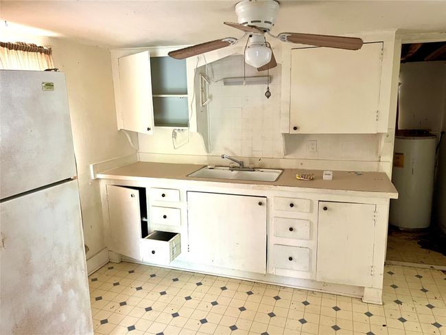 Kitchen featuring freestanding refrigerator, water heater, a ceiling fan, and light countertops | Image 8