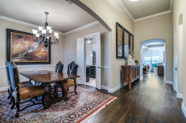 The spacious dining area has architectural design elements and a beautiful iron chandelier. | Image 6