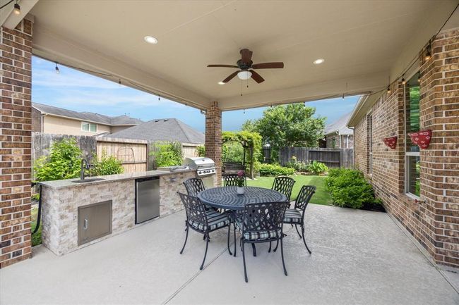 Enjoy your dinners under this extended roofline patio with outdoor kitchen featuring a Bull Grill, twin burner stovetop, sink and fridge | Image 42