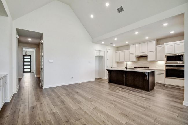 Kitchen featuring appliances with stainless steel finishes, high vaulted ceiling, white cabinetry, light countertops, and recessed lighting | Image 22