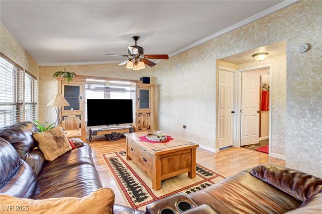 Living area with wallpapered walls, healthy amount of natural light, light wood-style floors, a ceiling fan, and ornamental molding | Image 9