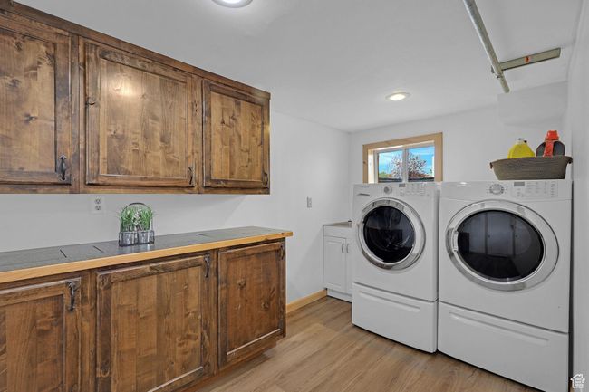 Washroom featuring cabinet space, washer and dryer, light wood finished floors, recessed lighting, and baseboards | Image 26