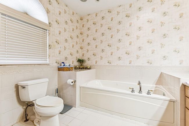 Full bathroom featuring a wainscoted wall, wallpapered walls, toilet, and a bath | Image 18