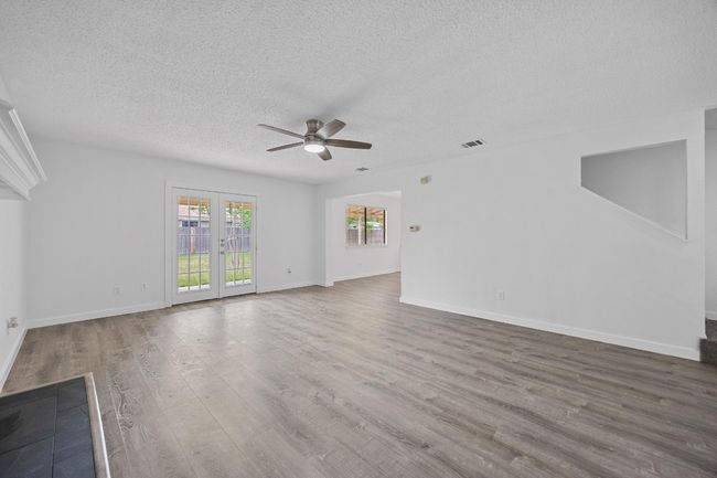 Unfurnished living room featuring a ceiling fan, wood finished floors, a textured ceiling, baseboards, and visible vents | Image 5