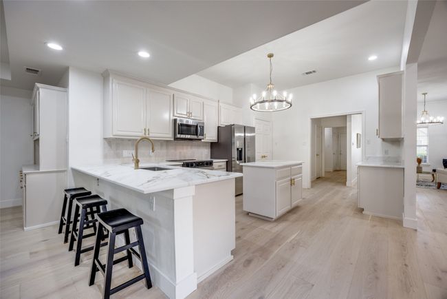 Kitchen with a chandelier, appliances with stainless steel finishes, a peninsula, a kitchen island, and recessed lighting | Image 9