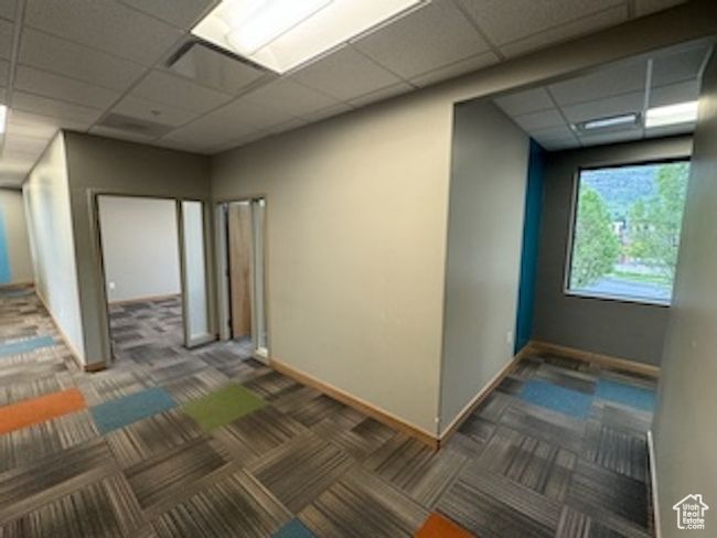 Carpeted empty room featuring a drop ceiling and baseboards | Image 28