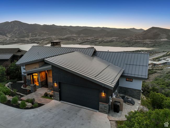 Modern home featuring a standing seam roof, stone siding, a garage, and driveway | Image 79